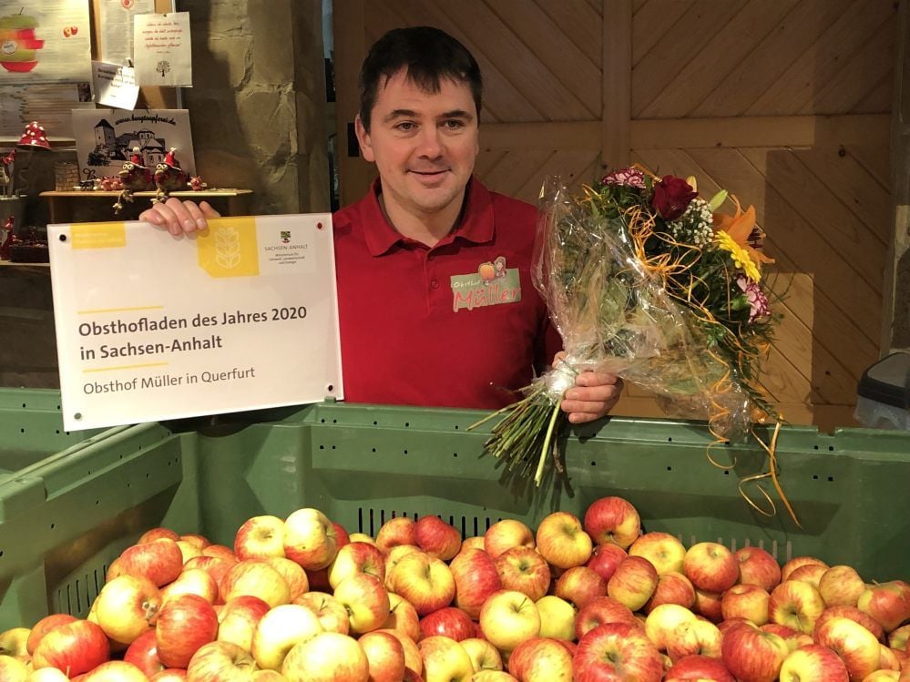 Obsthof-Chef Alexander Müller bekam im Rahmen der Auszeichnung Blumen und ein Schild, welches am Obsthofladen angebracht werden kann.