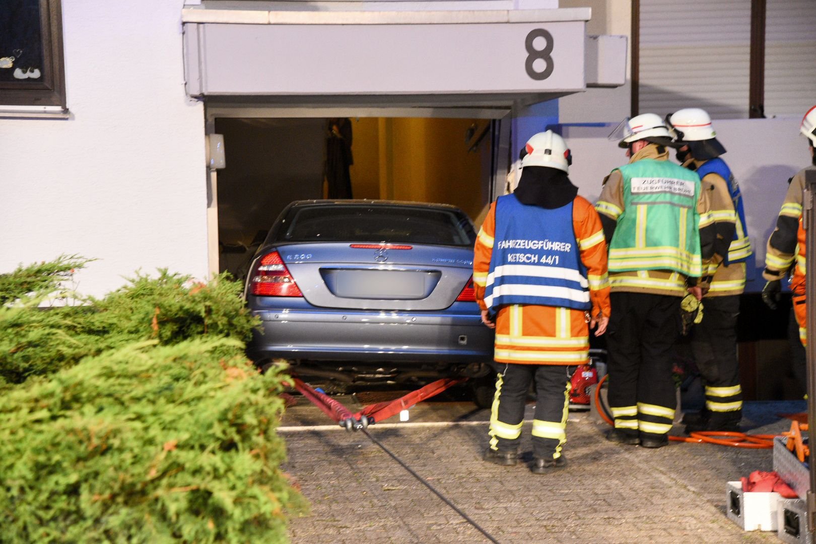 Feuerwehrmänner stehen in Brühl (Baden-Württemberg) an einem Fahrzeug, das von seinem 82-jährigen Fahrer in einen Hauseingang gesteuert worden war.
