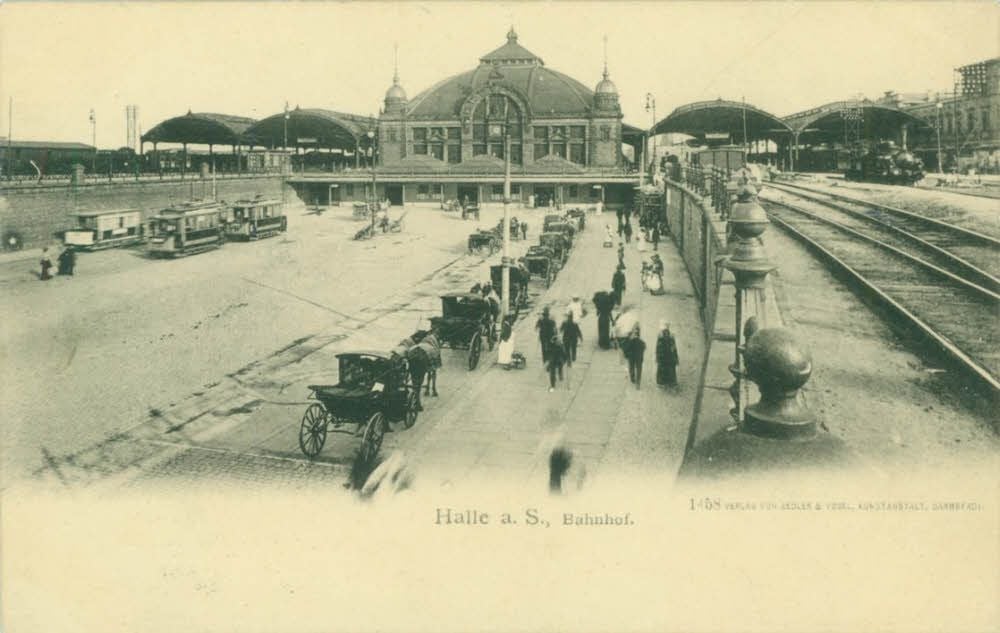 Diese Postkarte zeigt eine Aufnahme des Bahnhofsvorplatzes mit der erweiterten Vorhalle des Bahnhofsgebäudes um 1902.