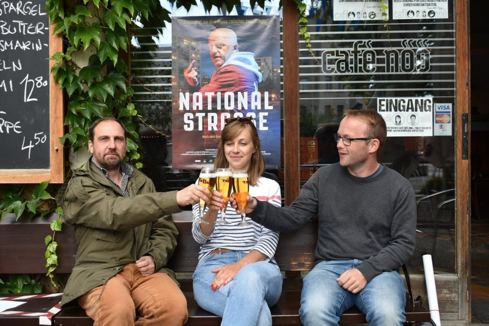Prost im Nöö: Produzent Eike Goreczka, Projektentwicklerin Claudia Hoffmann von 42film und Techniker Christoph Behling v.l.) stoßen bei letzten Vorbereitungen für die Premiere des Films „Nationalstraße“ an. Der Streifen läuft erstmals am Dienstag im Autokino.