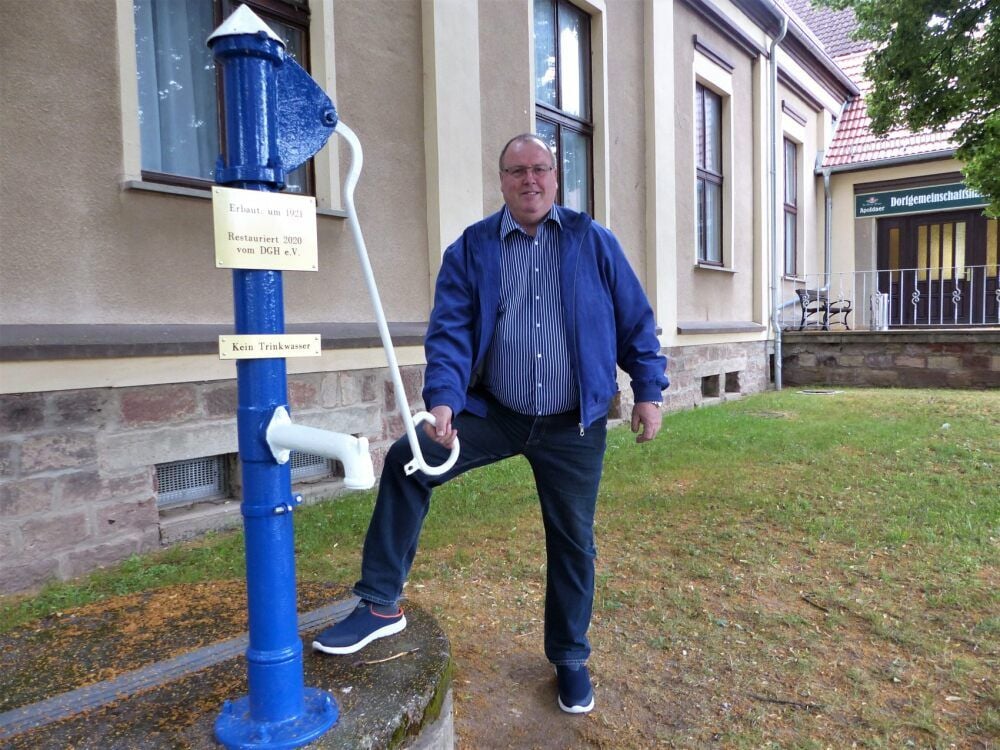 Uwe Thiel, Vorsitzender des Vereins zur Erhaltung des Dorfgemeinschaftshauses, freut sich über die restaurierte Schwengelpumpe von Burgscheidungen.