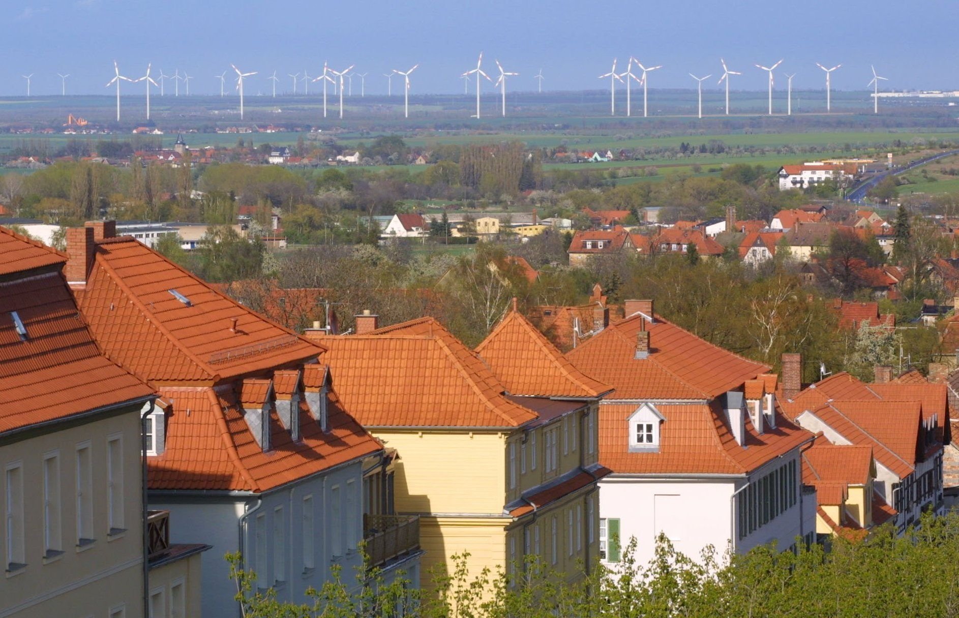 Blick vom Ballenstedter Schloss über die Dächer der Harzstadt Ballenstedt (Landkreis Quedlinburg) auf einen großen Windpark am Horizont.