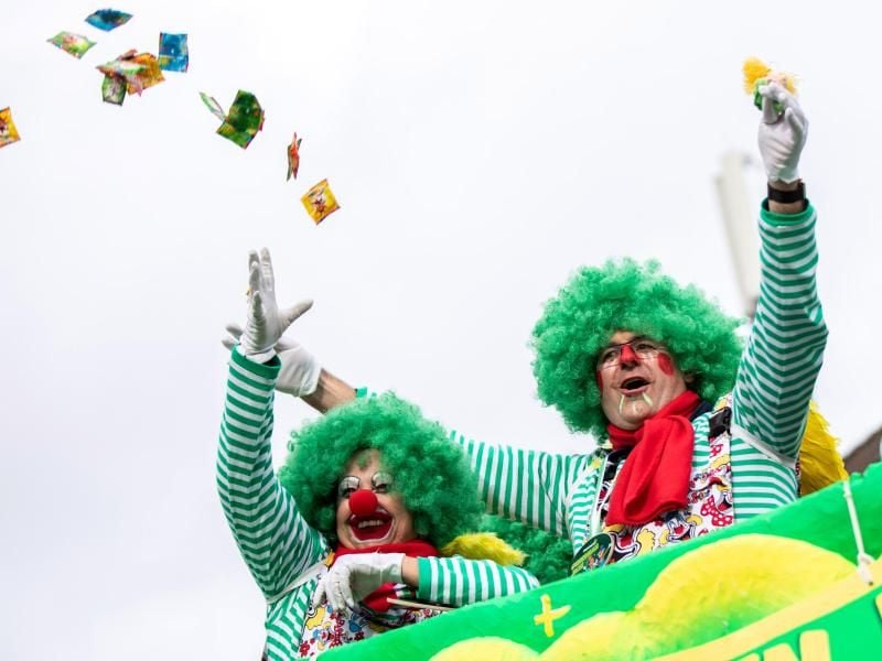 Karnevalisten feiern bei einem Rosenmontagszug und werfen mit Kamelle. Foto: Marcel Kusch/Archiv
