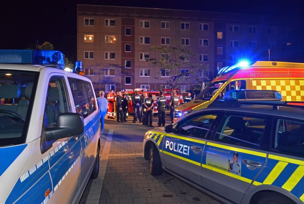 Polizei, Feuerwehr und Krankenwagen stehen nach dem Feuer vor dem Wohnblock in der Wilhelm-Bestel-Straße in Aschersleben.