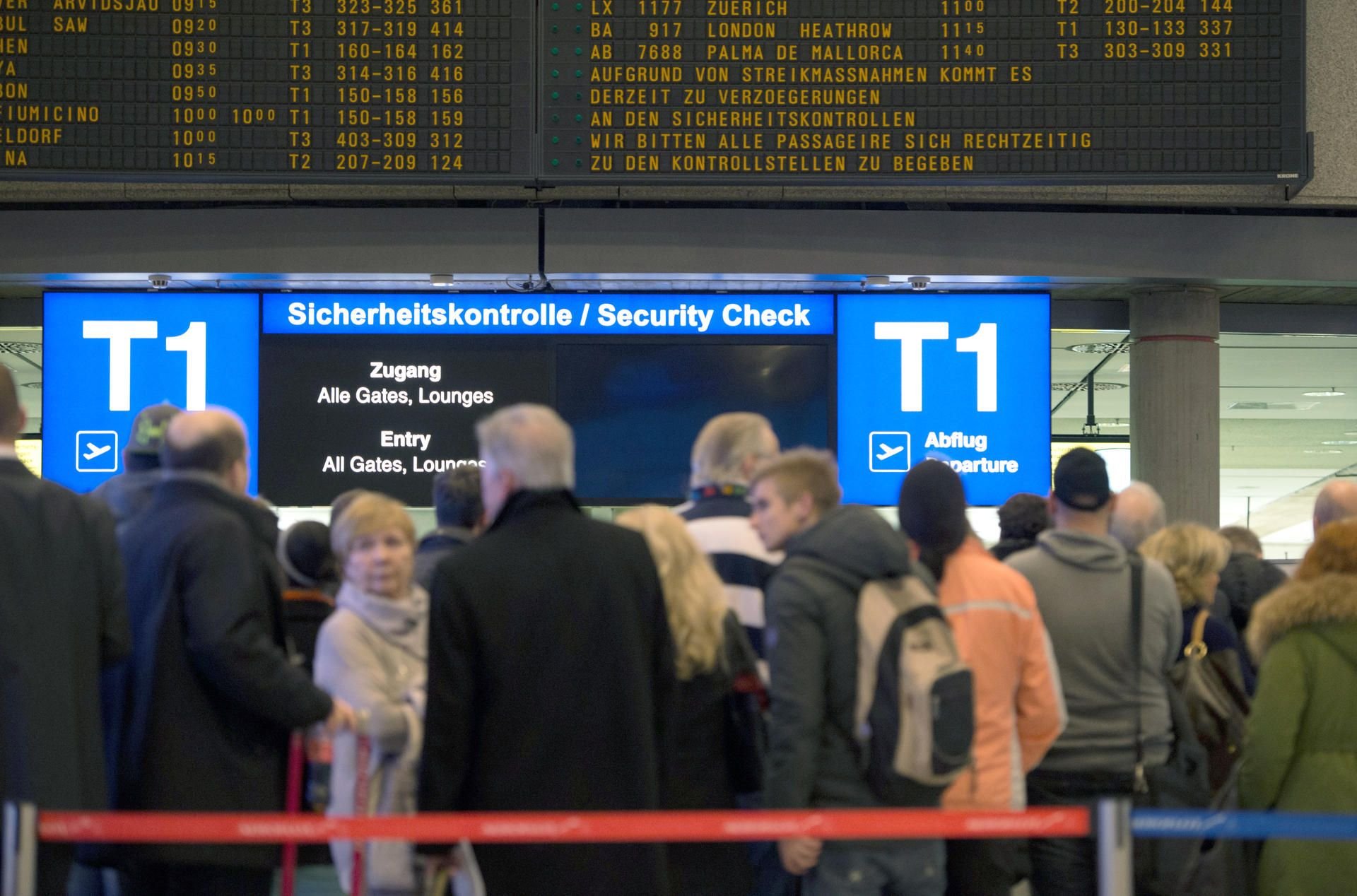 Reisende warten auf einem Flughafen in einer Schlange an der Sicherheitskontrolle. Verdi hat auch an den mitteldeutschen Flughäfen zum Streik aufgerufen.
