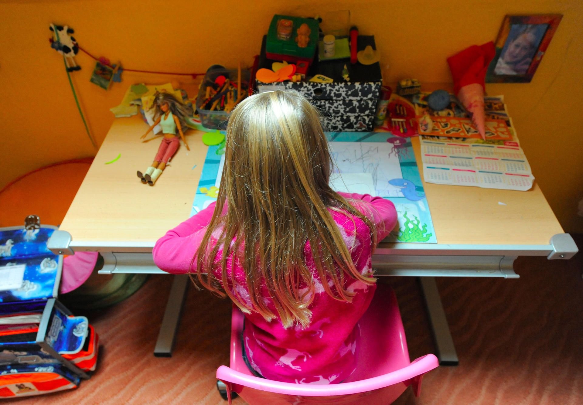 Ein Pflegekind sitzt in seinem Kinderzimmer bei den Hausaufgaben.