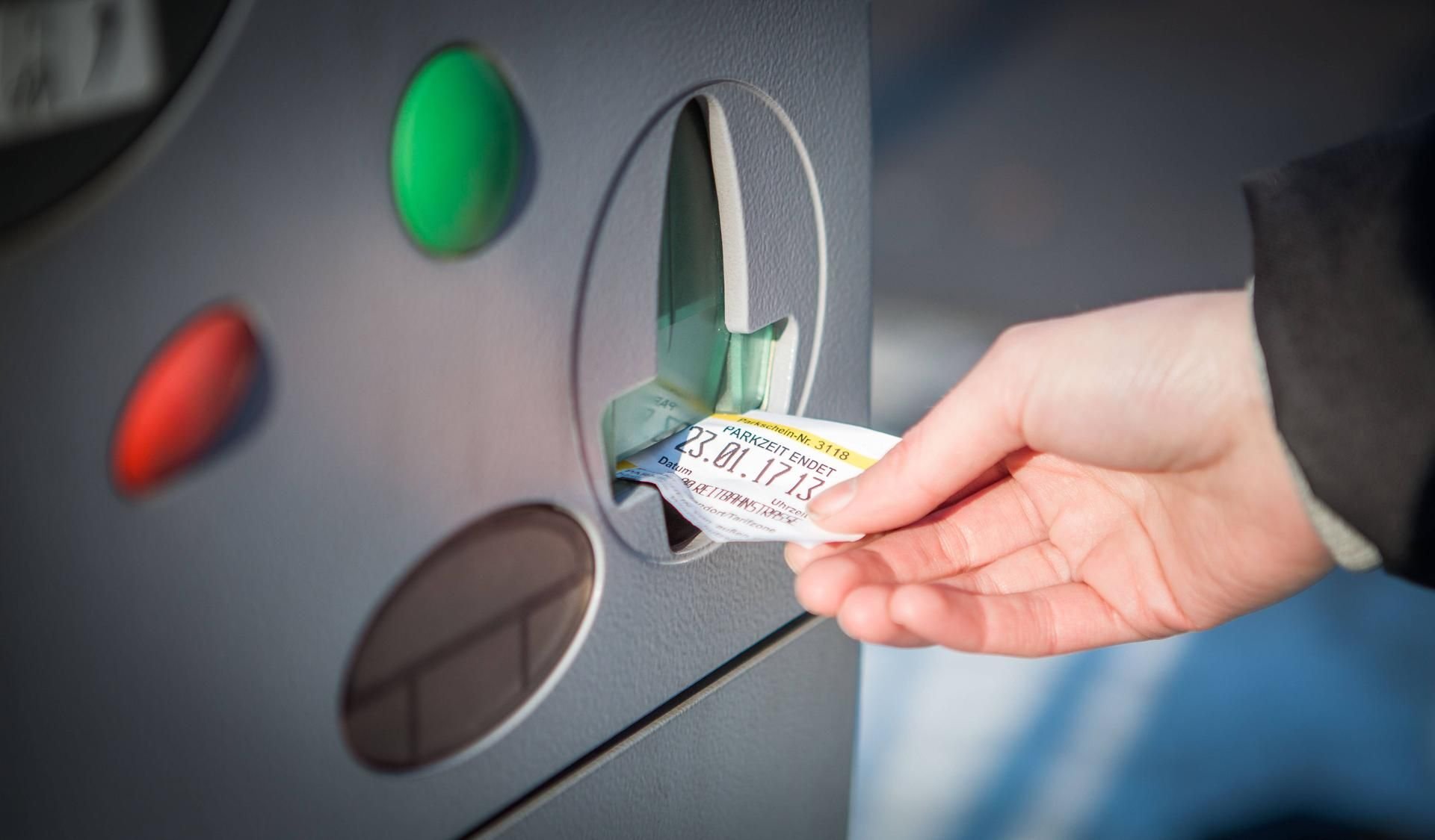 Ein Autofahrer zieht einen Ticket aus dem Parkautomat.