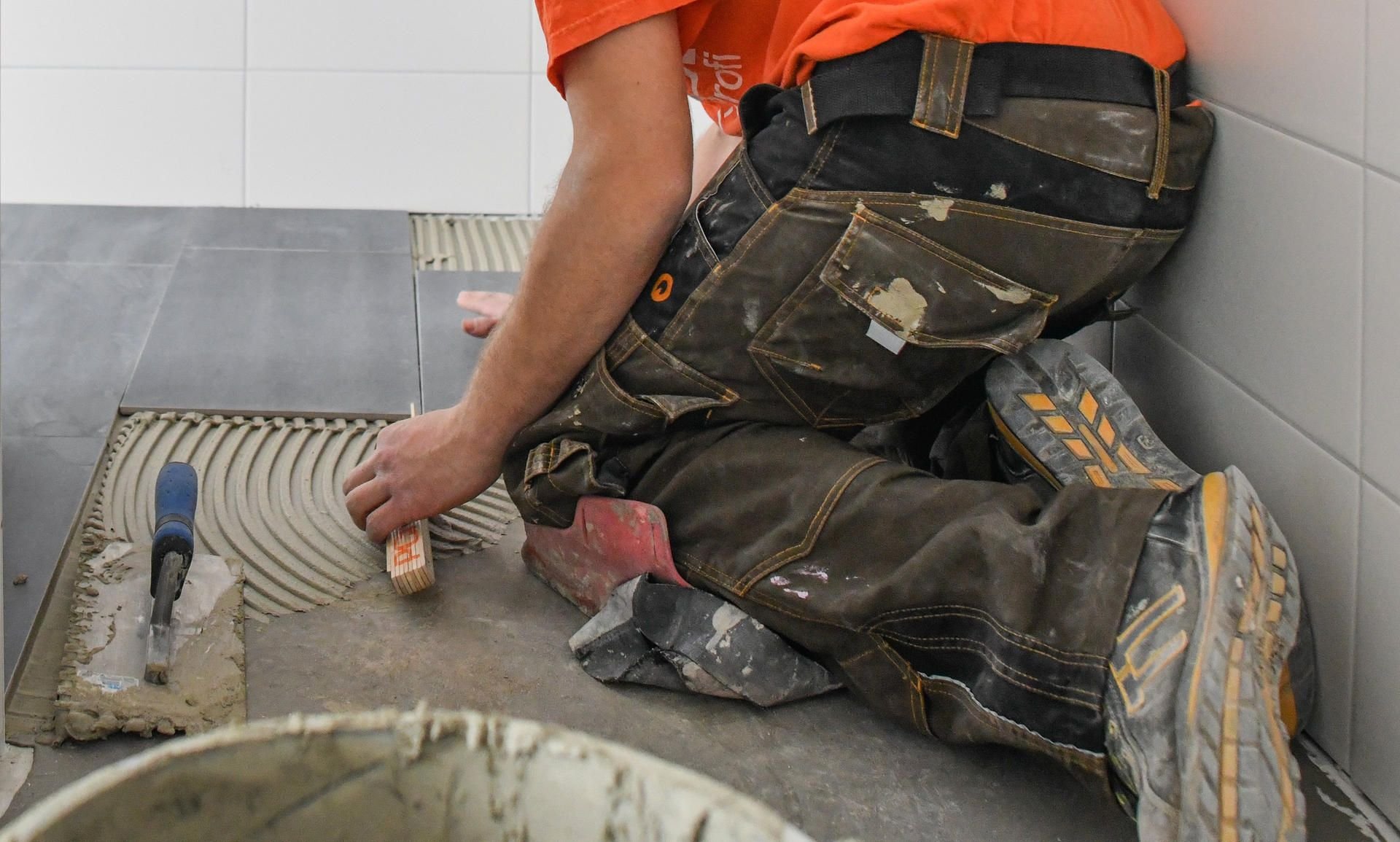 Ein Fliesenleger bei der Arbeit: Angesichts des Fachkräftemangels gerade in vielen Berufen des Bau- und Ausbauhandwerks müssen Kunden immer länger auf den Handwerker warten.