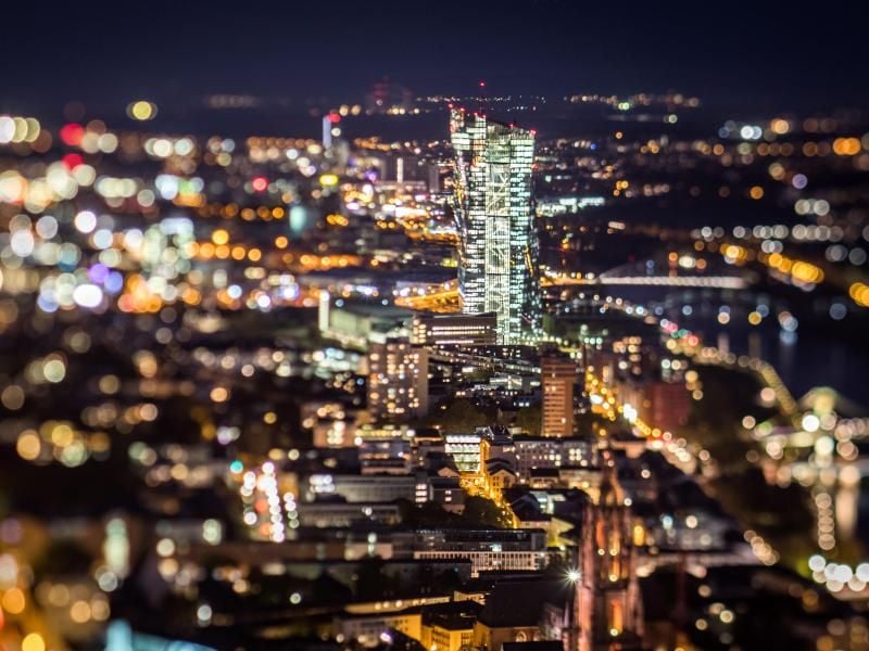 Frankfurt am Main: Die Zentrale der Europäischen Zentralbank (EZB) steht im letzten Licht des Tages zwischen den beleuchteten Häusern der Stadt. Foto: Frank Rumpenhorst/Illustration