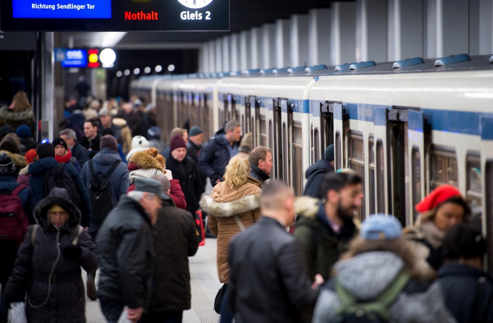 Menschen steigen auf einem Bahnsteig in München in eine U-Bahn.