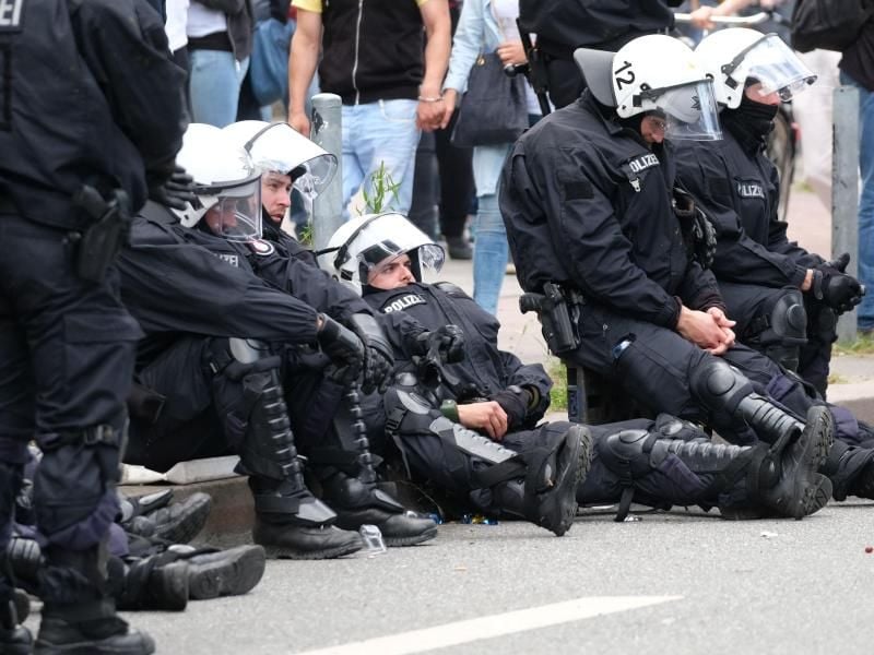Völlig erledigt: Polizisten ruhen sich am Rande der Demonstration „Grenzenlose Solidarität statt G20” aus. Foto: Sebastian Willnow