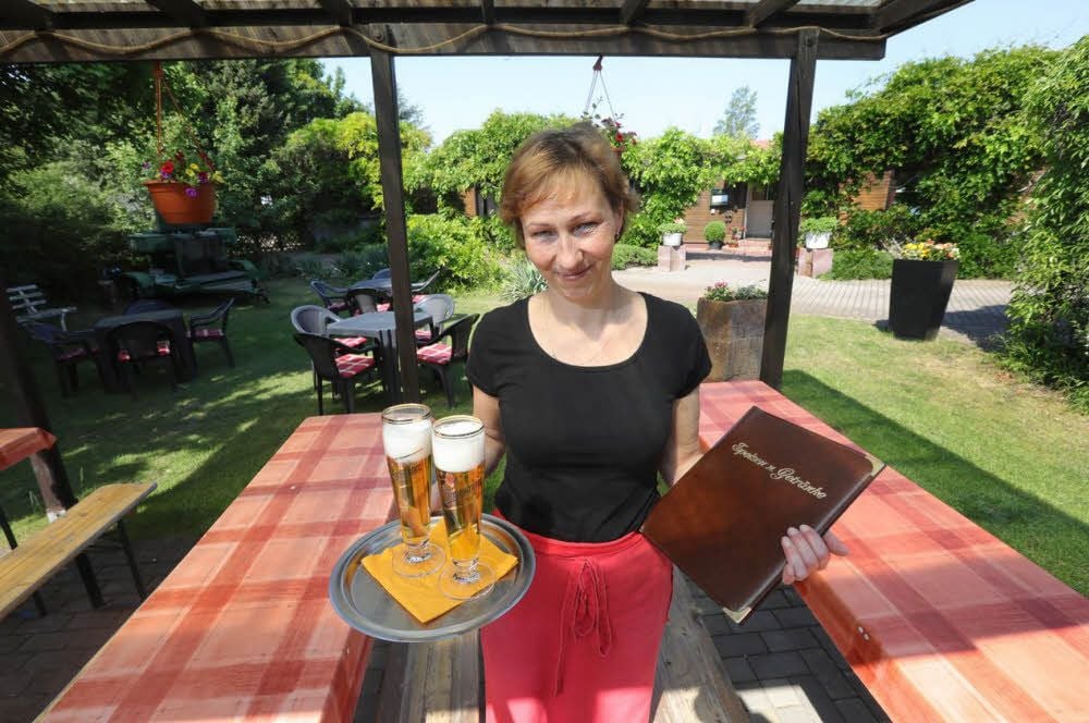Diana Rickelt im Biergarten ihrer Gaststätte, die inmitten einer grünen Idylle gelegen ist.