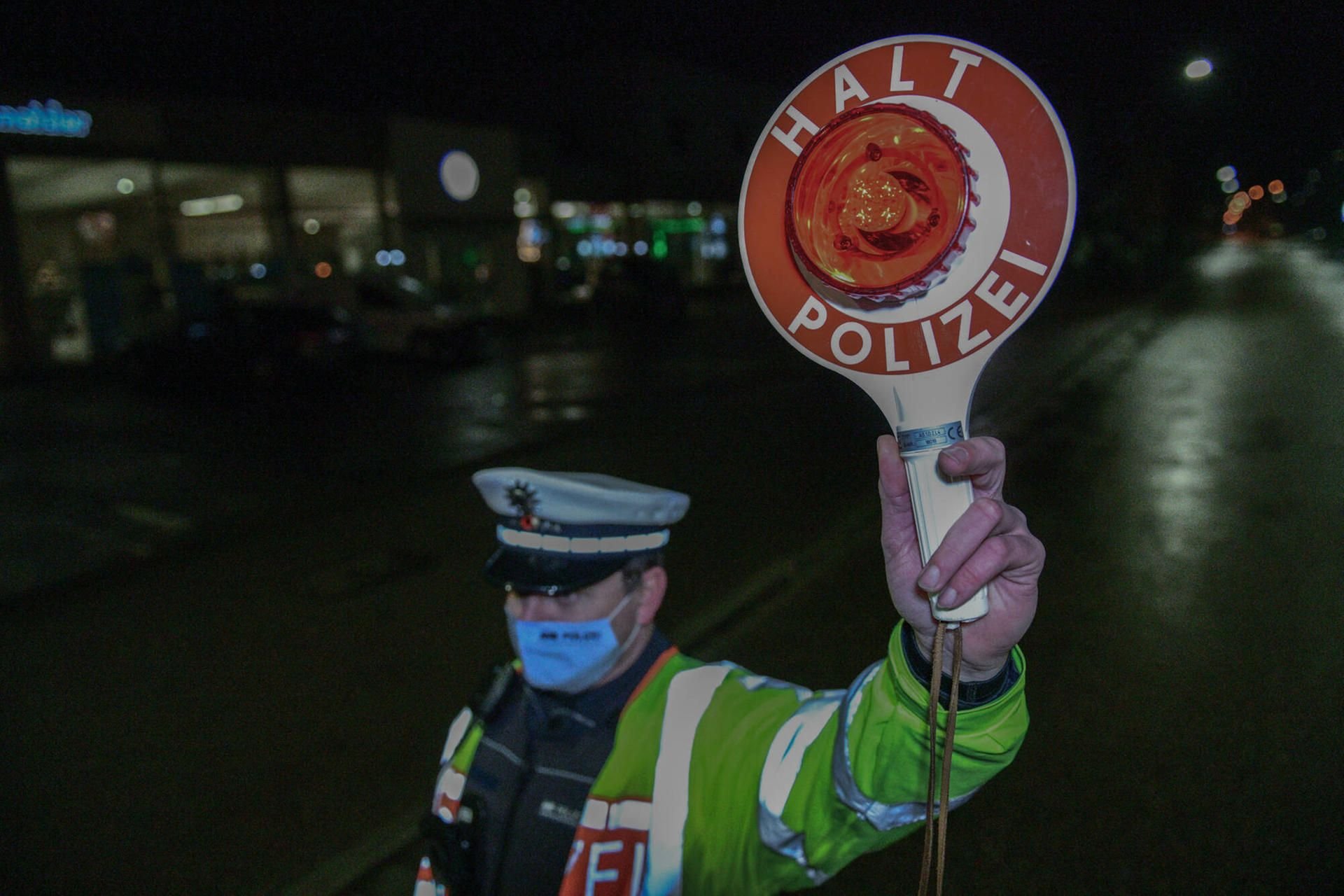 Ein Polizist mit Maske stoppt Fahrzeuge (Symbolbild)
