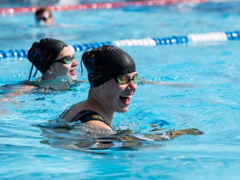 Zwei Schwimmerinnen lachen im 50-Meter-Becken im Freibad. Foto: Swen Pförtner/dpa/Archivbild