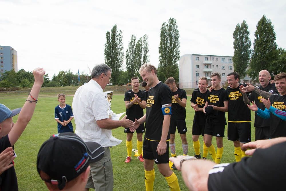 Staffelleiter Detlef Herrmann gratuliert 05-Kapitän Patrick Heldt und dessen Teamkollegen zur Meisterschaft und zum Landesliga-Aufstieg.
