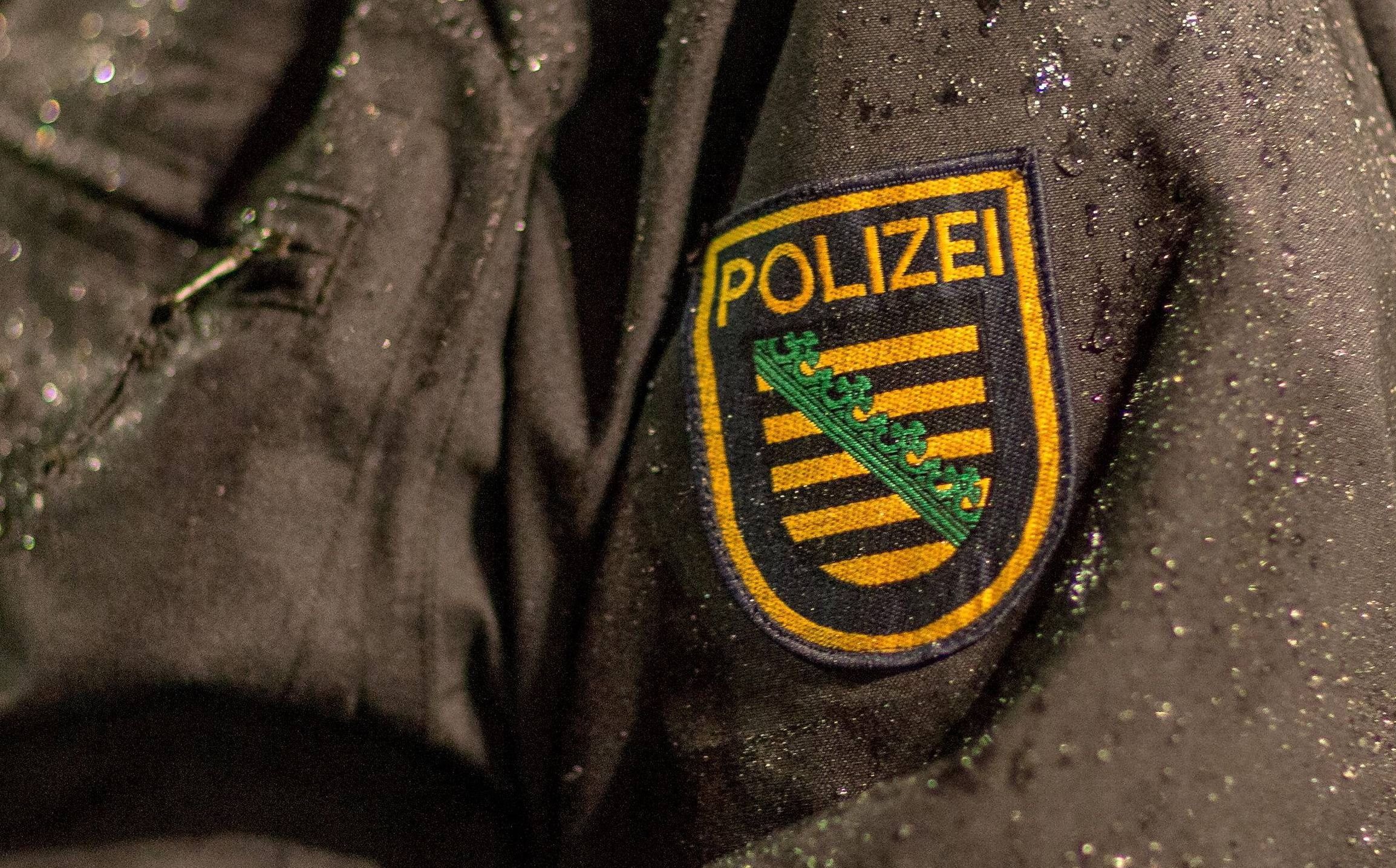 Symbolbild: Das Emblem der Polizei Sachsen an der Jacke eines Beamten.