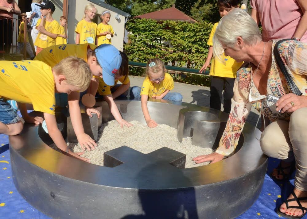 Carmen Dietrich (rechts) verteilt mit den Kindern der Kindertagesstätte „Benjamin Blümchen“ den Sand im Engel der Kulturen.