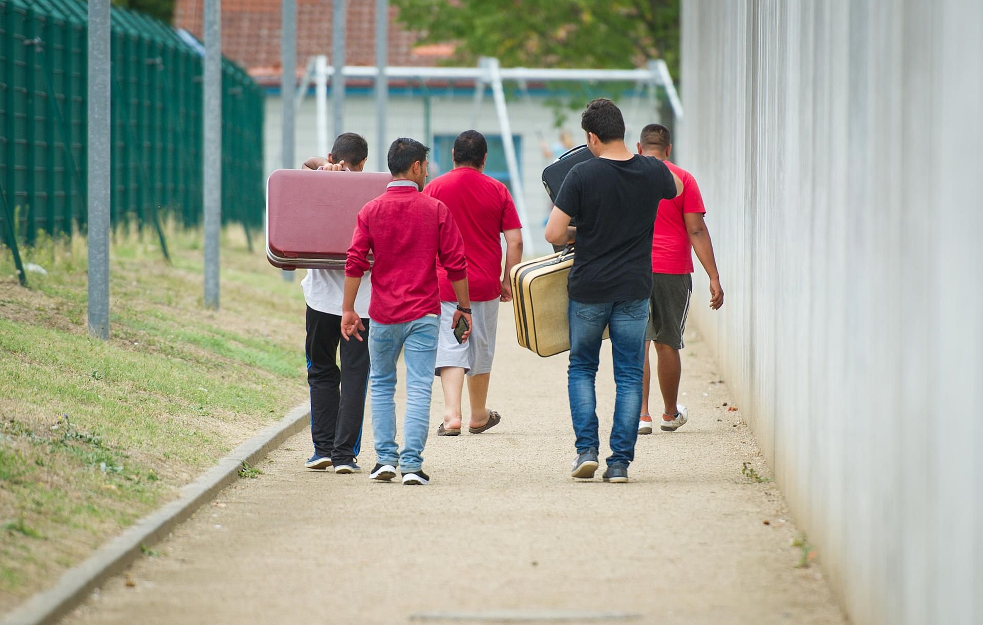 Flüchtlinge sind mit Koffern bepackt auf dem Weg zu einer Erstaufnahmeeinrichtung. (Symbolbild)