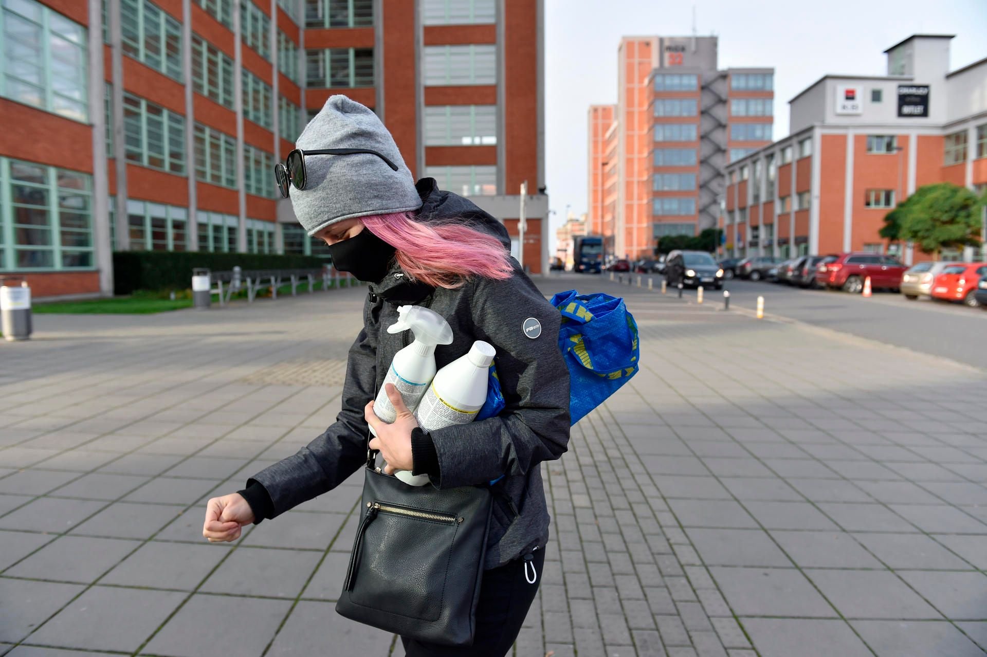 Eine Passantin trägt einen Mund-Nasen-Schutz während sie an einer Straße geht.