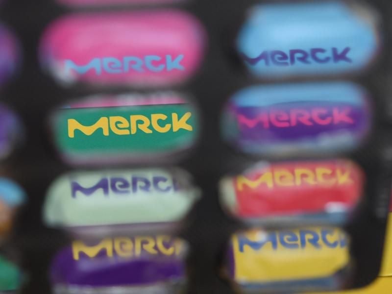 Verschiedenfarbige Merck-Logos sind durch eine Tablettenverpackung zu sehen. Foto: Arne Dedert/Archiv