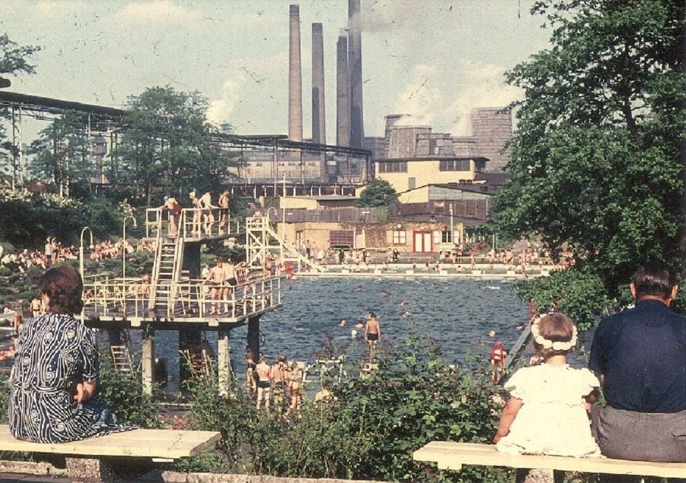 Von der Anhöhe aus, wo sich der Sanitärtrakt samt Umkleidekabinen und der Imbiss befanden, hatte man einen weiten Blick über das Freibad. Im Hintergrund sind die Anlagen des Chemiebetriebes zu sehen.