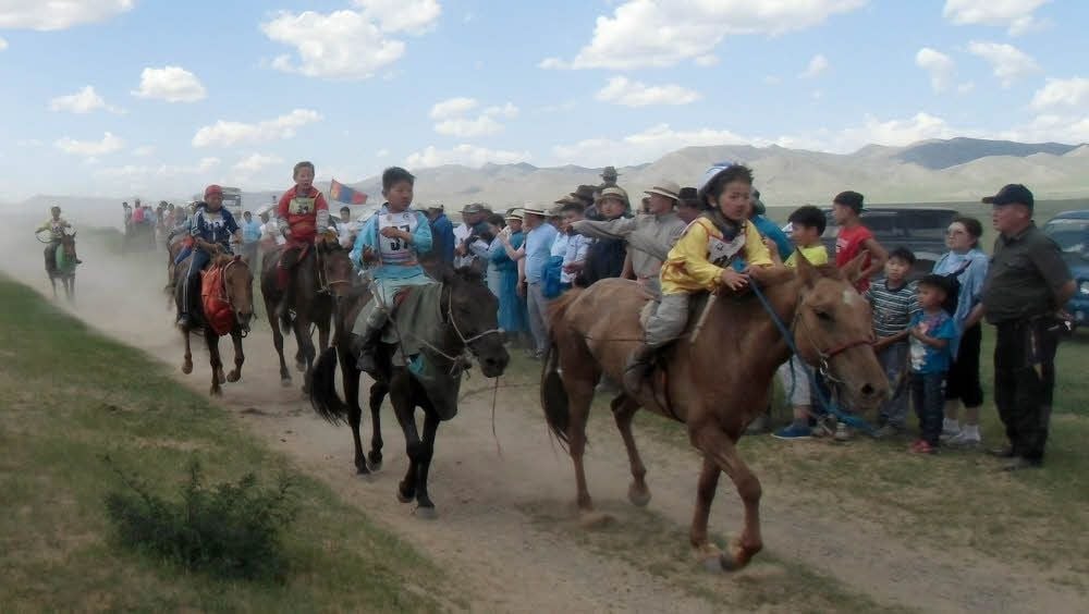 Ein Pferderennen während eines Naadam-Festes (Sommer-Volksfest) mit Kindern als Reiter.