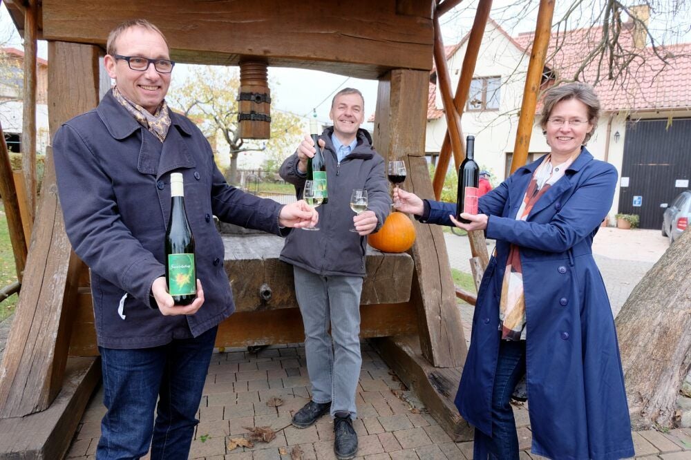 Kustos Jörg Bielig (l.), Winzer Ingo Hanke und Geschäftsführerin Kerstin Aleithe präsentieren den Wein, der in Wittenberg verkauft wird.