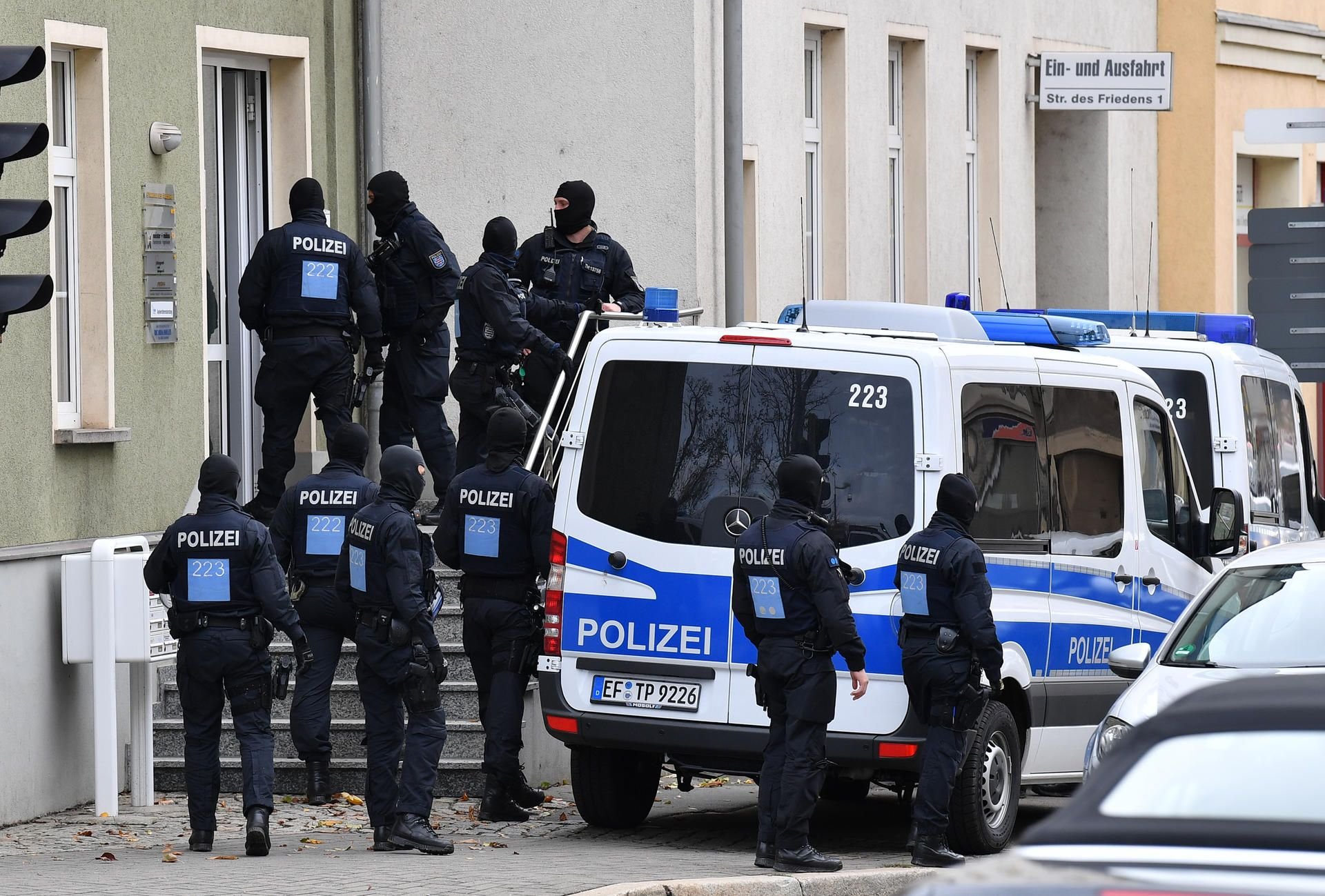 Polizisten stehen vor einem Geschäftshaus in der Straße des Friedens. In mehreren Orten in Ostthüringen und Sachsen haben Polizei, Landeskriminalamt und Zoll am Dienstag Wohnungen und Geschäftsräume durchsucht.