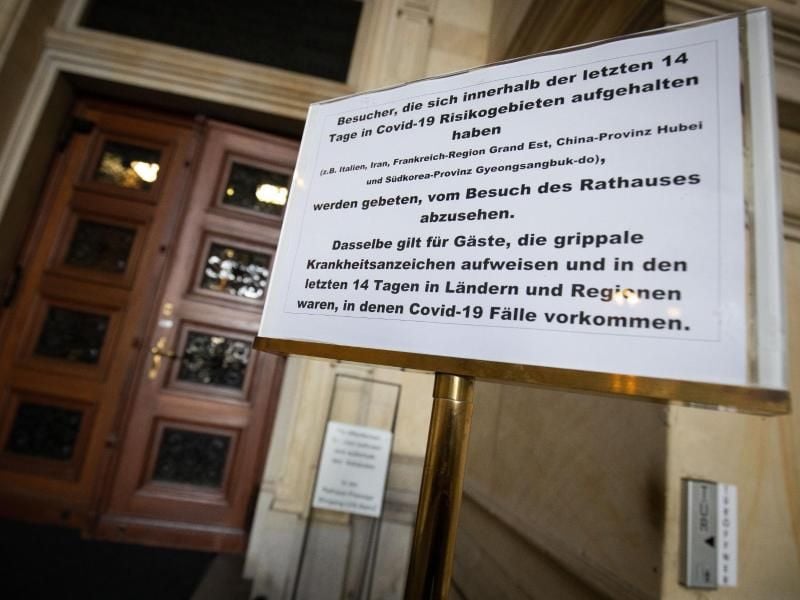 Ein Hinweisschild zur Corana-Situation steht am Haupteingang zum Rathaus. Foto: Christian Charisius/dpa