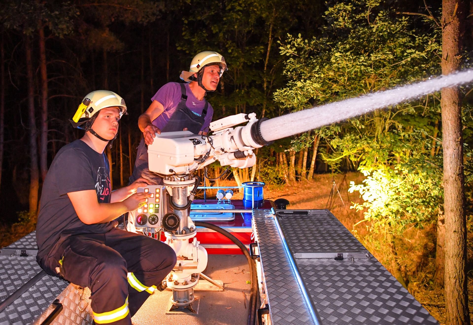 Klausdorf: Kameraden der Freiwilligen Feuerwehr Schlieben löschen mit einer Wasserspritze auf dem Dach ihres Fahrzeuges einen Waldbrand nahe Klausdorf.