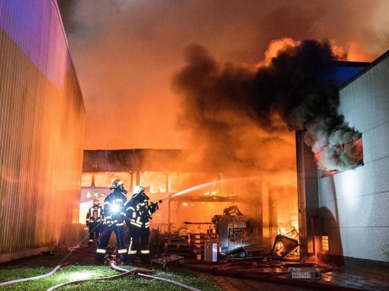 Feuerwehrleute löschen eine brennende Lagerhalle in Barsbüttel. Foto: Daniel Bockwoldt/dpa