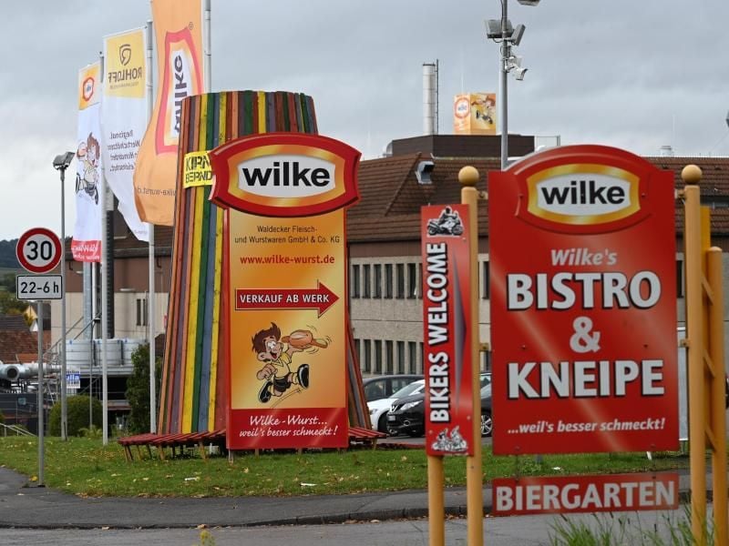 Firmenschilder kennzeichnen die Einfahrt zum Werksgelände des nordhessischen Wurstherstellers Wilke. Foto: Uwe Zucchi/dpa/Archivbild