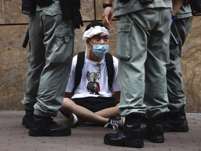 Bereitschaftspolizisten stehen im Hongkonger Central District um einen auf dem Boden sitzenden Demonstranten. Foto: Kin Cheung/AP/dpa