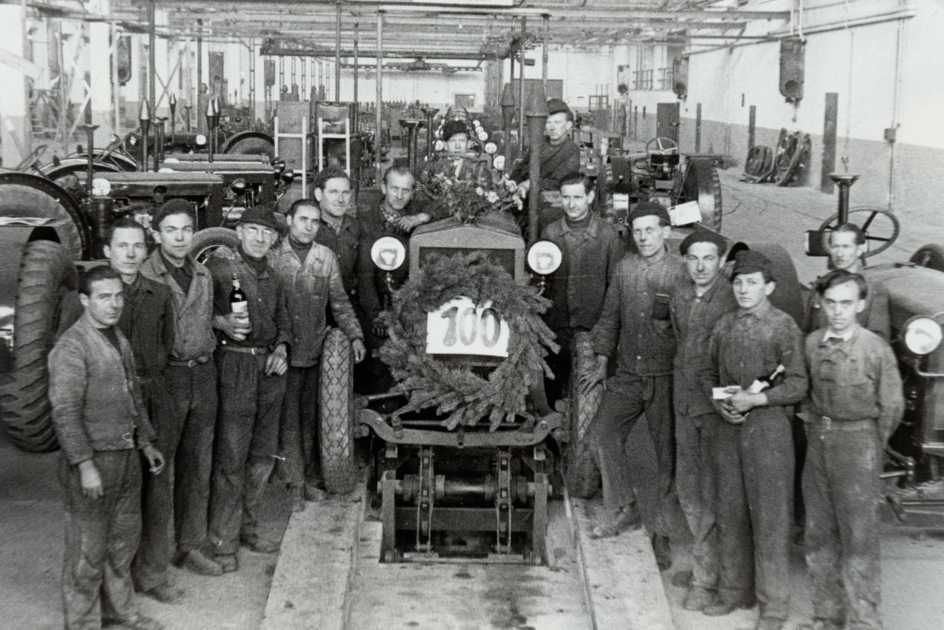 Arbeiter stehen während der Feier im Werk Horch anläßlich der Fertigstellung des 100. Traktors 1949 neben einem Traktor.