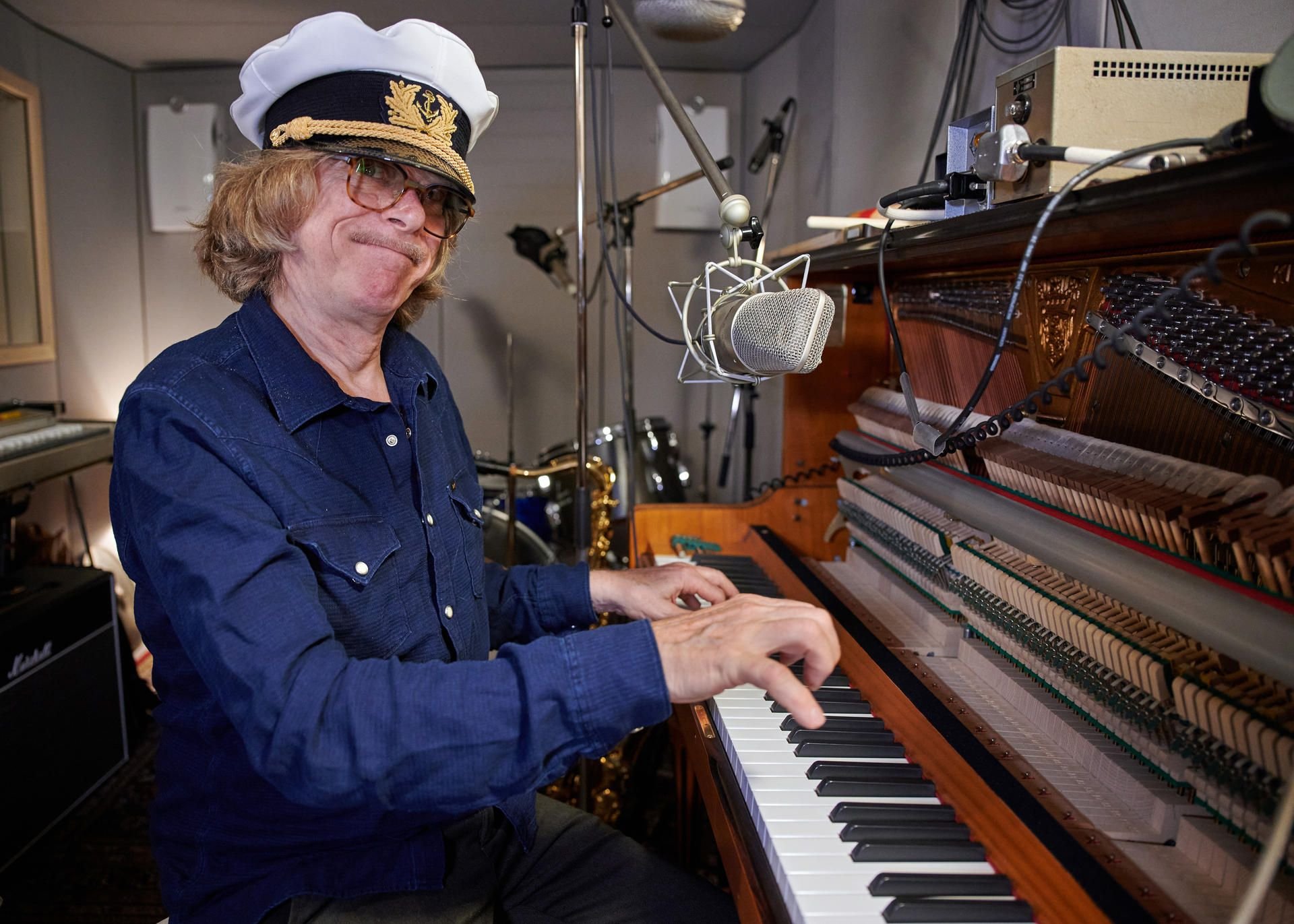 Der Musiker und Komiker Helge Schneider sitzt in einem kleinen Studio am Klavier.