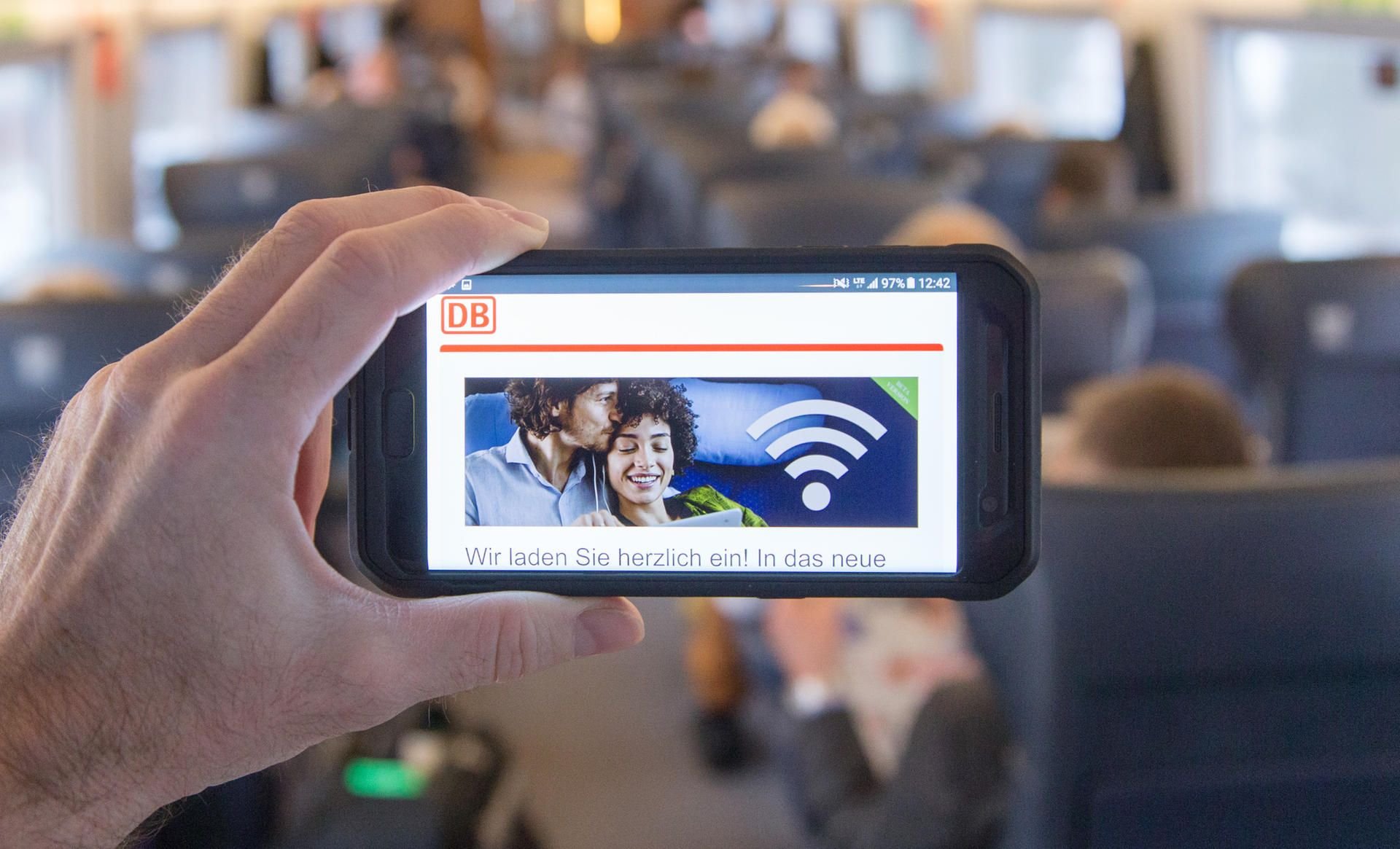 Das Display eines Smartphones mit WLAN-Hinweis ist in einem Abteil eines Zuges der Deutschen Bahn zu sehen.