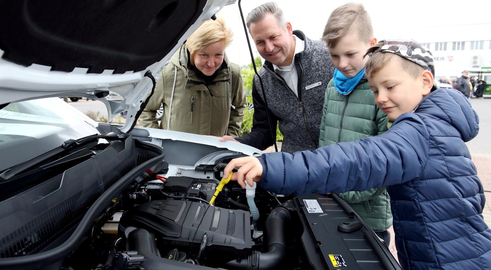 Anja Roßberg (von links), Mathias Lehmann, Dennis und David schauen sich den Motorraum des neuen VW T-Cross an.