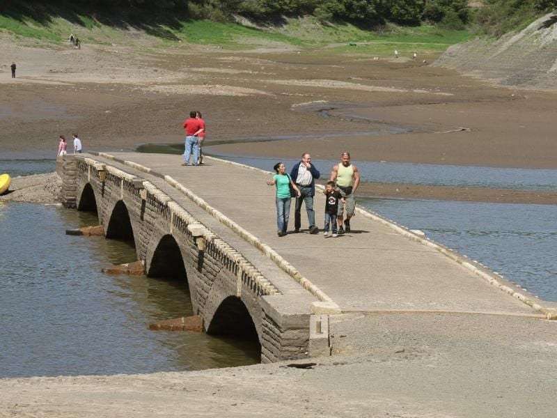 Touristen laufen am Edersee bei Asel über eine Brücke. Foto: Uwe Zucchi/Archiv