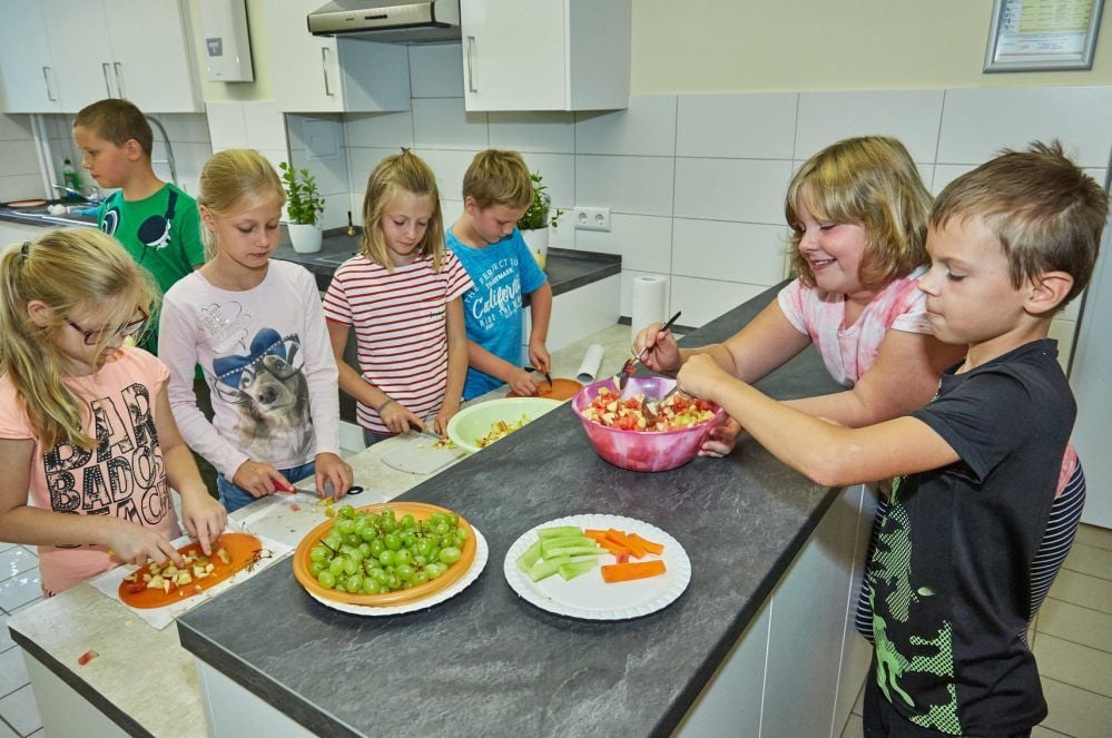Die Mädchen und Jungen der Klasse 3a schnippeln fleißig Obst und Gemüse in der neuen Küche.