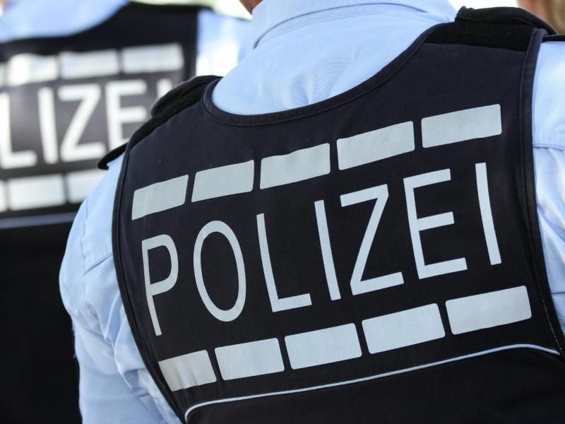 Ein Polizist trägt eine Weste mit der Aufschrift „Polizei”. Foto: Silas Stein