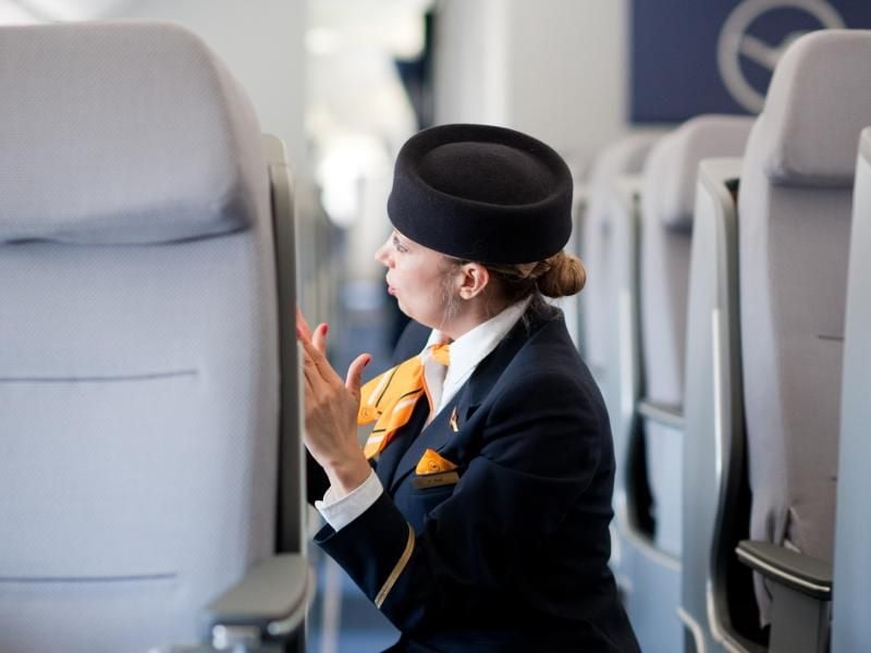 Eine Flugbegleiterin checkt die Sitzreihen eines Flugzeugs (Symbolbild)