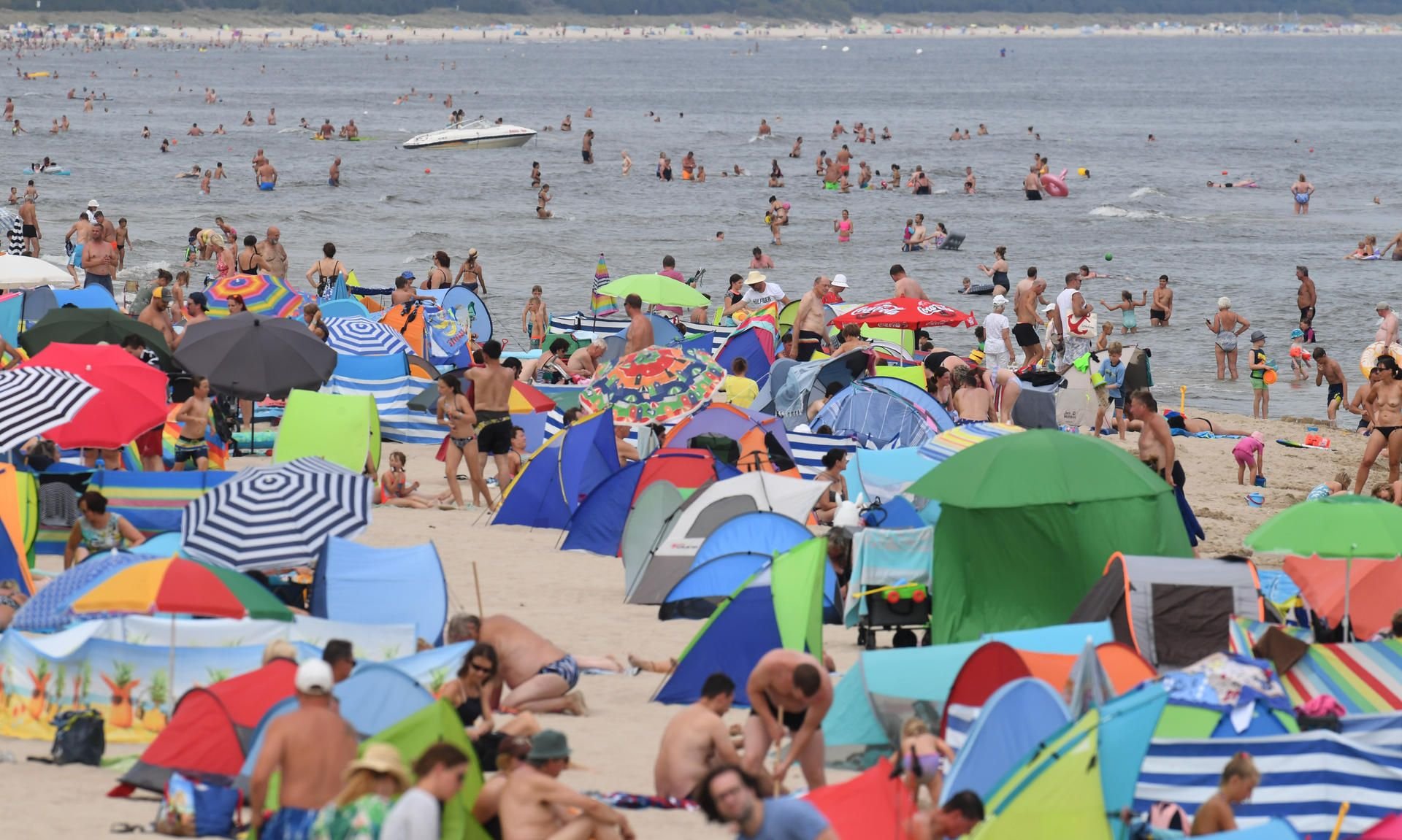 Zinnowitz: Am Ostseestrand vor der Seebrücke haben sich zahlreiche Badegäste am Strand niedergelassen, oder genießen das Wasser.