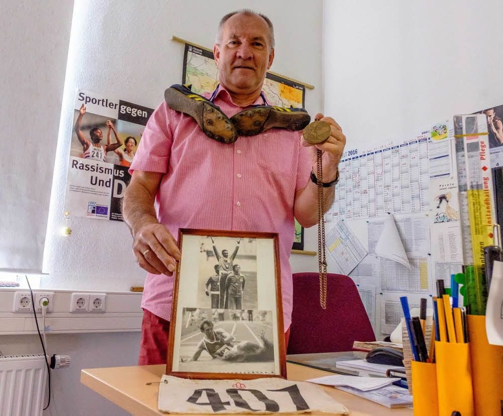 Frank Wartenberg mit Medaille und Olympia-Utensilien in seinem Büro. Vor 40 Jahren holte er im Weitsprung eine Medaille.