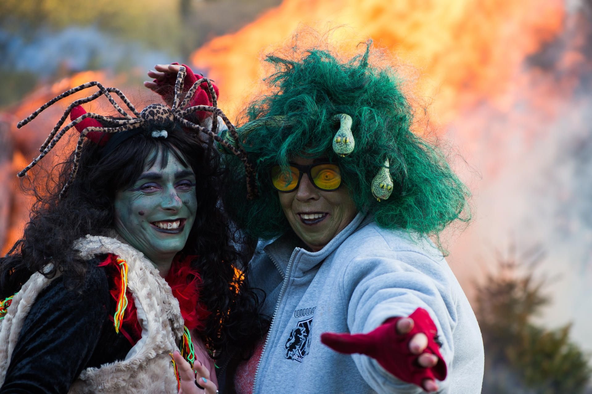 Die als Hexen kostümierten Frauen Annika und Anita stehen bei der Walpurgisfeier 2017 in Elend (Harz) vor einem Feuer.