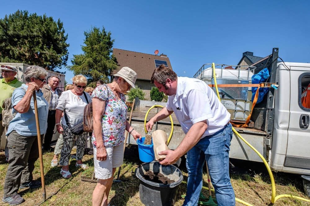 Bürgermeister Enrico Schilling gibt den Blühwiesensamen aus.