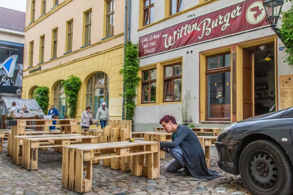 Lydia Grauss schraubt die Sitzmöbel der Burger Bar in der Innenstadt von Wittenberg auseinander.