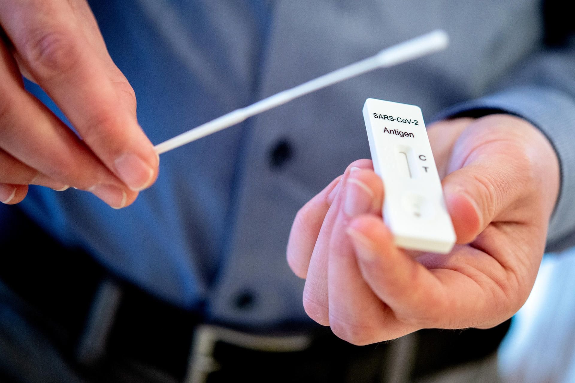 Ein Mann hält einen Schnelltest zur Erkennung des Coronavirus und ein Teststäbchen in einem Pflegeheim in den Händen.