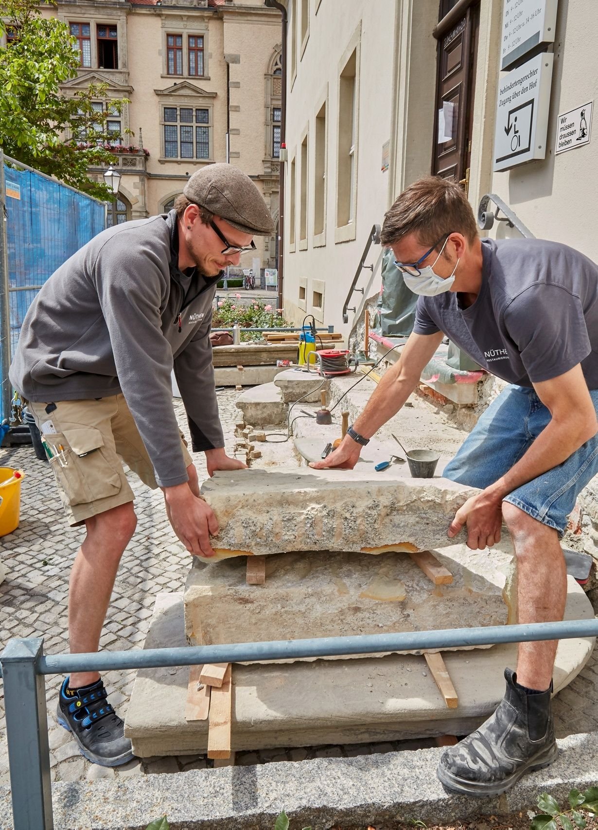 Die Steinmetze Dominik Arendt und Georg Richter entfernen Sandsteinstufen von der Treppe am Haupteingang des Rathauses in Bernburg.