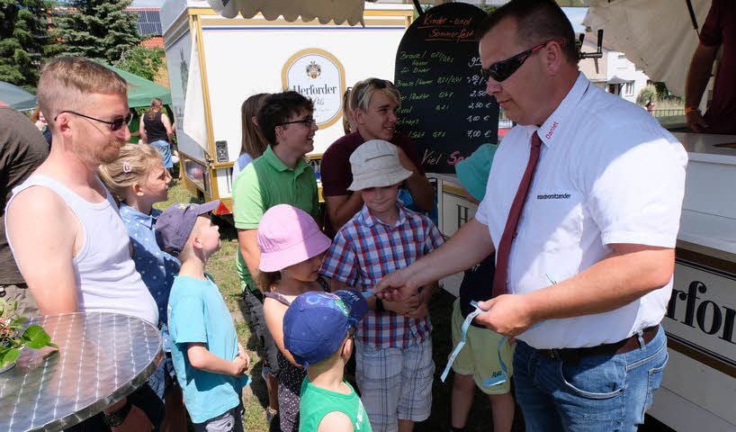 Organisator Daniel Siegel (rechts) vom Feuerwehrverein Zahna verteilt Verpflegungsmarken an die kleinen Besucher der Veranstaltung.