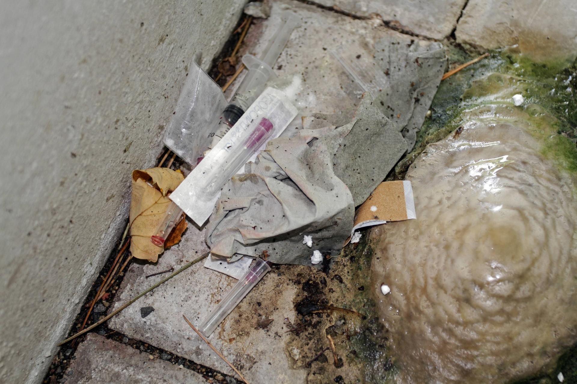 Utensilien von Junkies, die von Drogenabhängigen hinter einem Betonpfeiler zurückgelassen wurden.